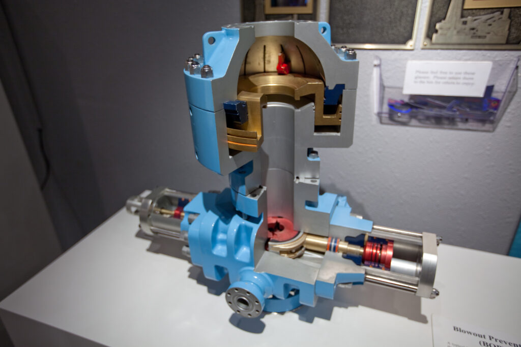 Cutaway blowout preventer exhibit showing internal sealing assemblies around a central pipe.