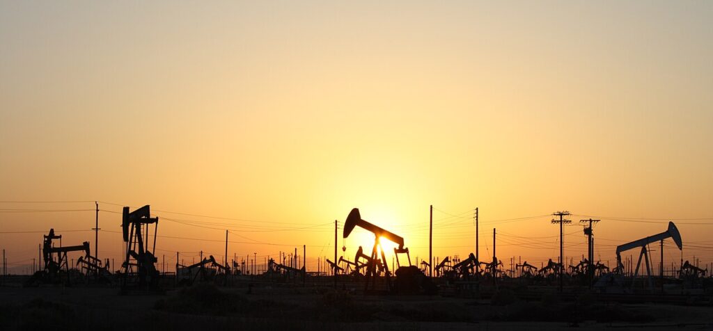 Several operating pumpjacks at Lost Hills Oil Field in California at sunset.
